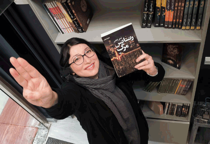 Zoha Kazemi holding her award winning book "Death Renaissance"